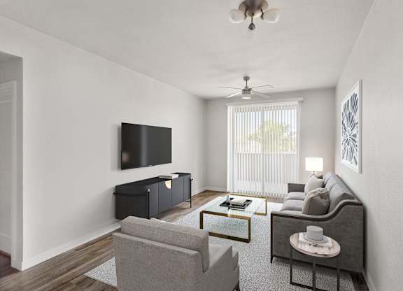 A living room with a grey couch, a coffee table, and a flat screen TV mounted on the wall.
