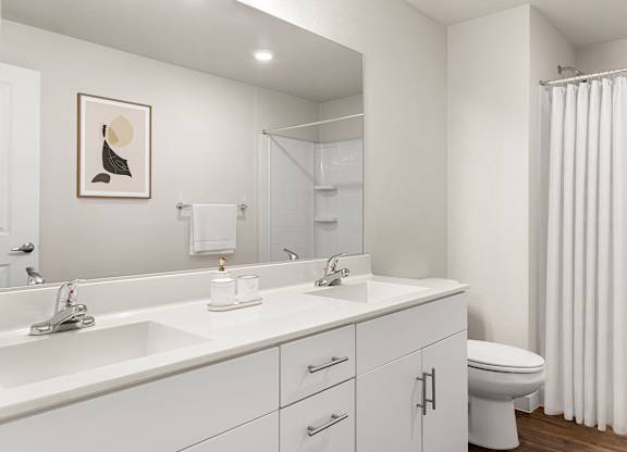 A white bathroom with a toilet, sink, and mirror.