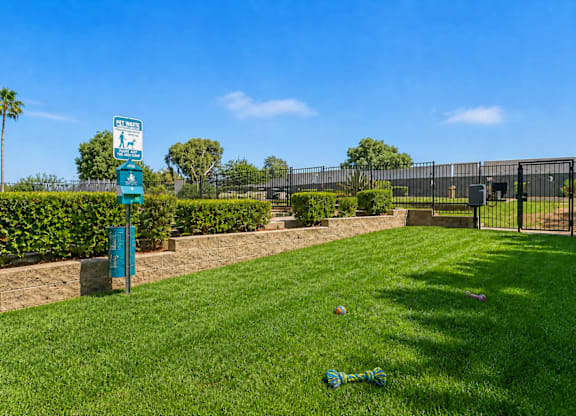 A blue sign with white text is on a post in a grassy area.