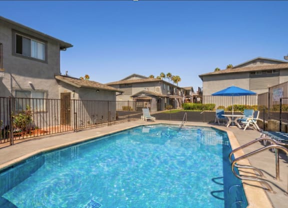 A swimming pool surrounded by a metal fence and chairs.