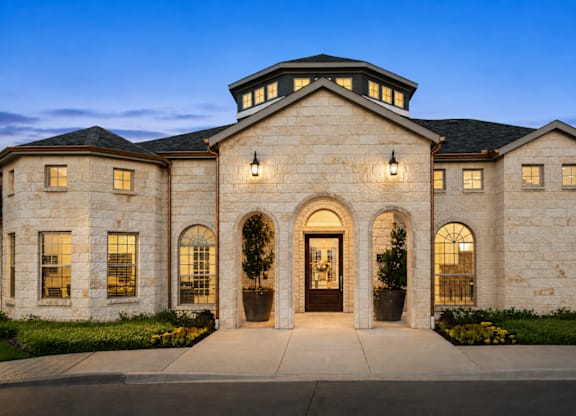 A large, beautifully lit house with a stone facade and a central entrance.