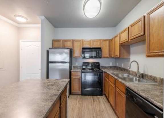 A kitchen with a black stove top oven and wooden cabinets.