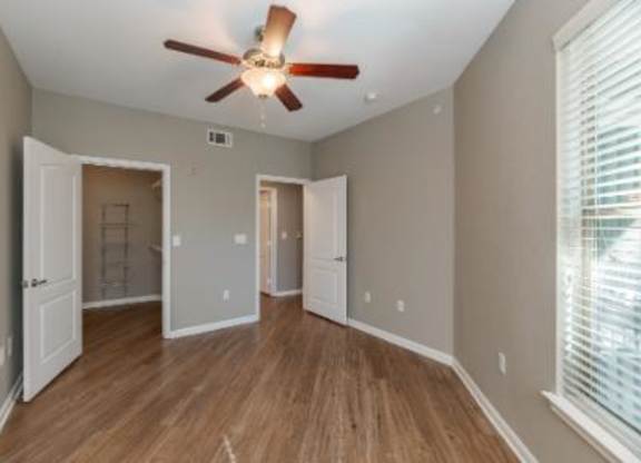 A room with a ceiling fan and wooden floors.