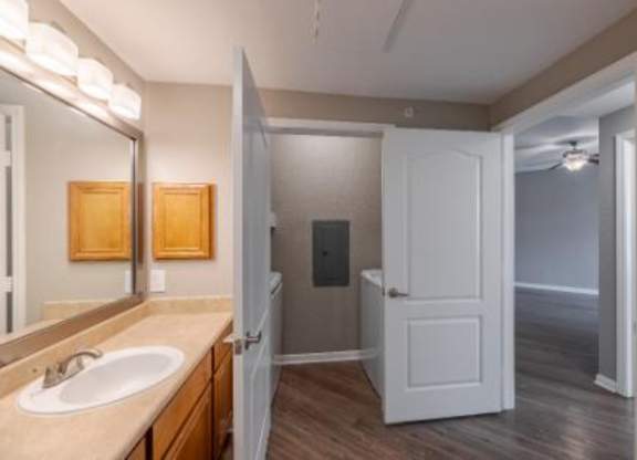 A bathroom with a sink, mirror, and a door.