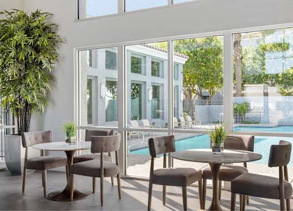 A table with chairs is in front of a glass wall.