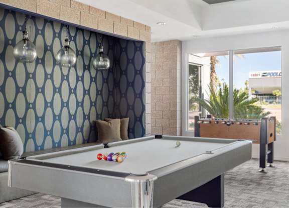 A pool table in a room with a blue patterned wallpaper.