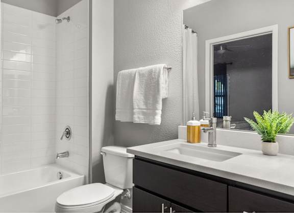 A white towel hangs on a wall above a white sink in a bathroom.