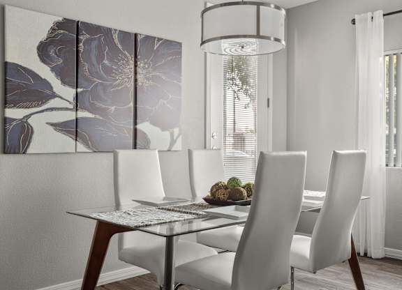 A dining table with four chairs and a decorative wall hanging.