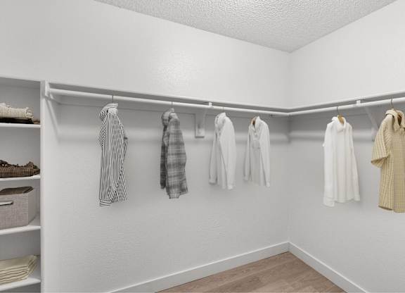 A white closet with clothes hanging on hangers.