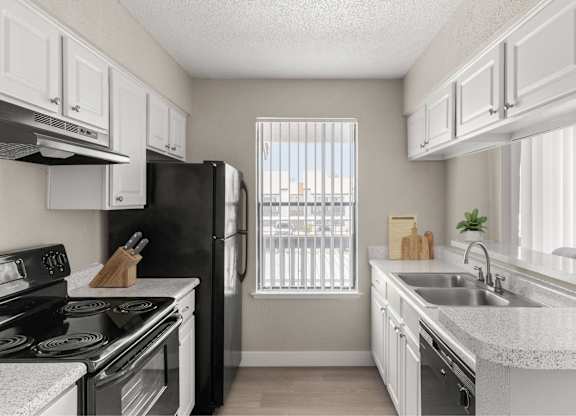 A kitchen with black appliances and white cabinets.
