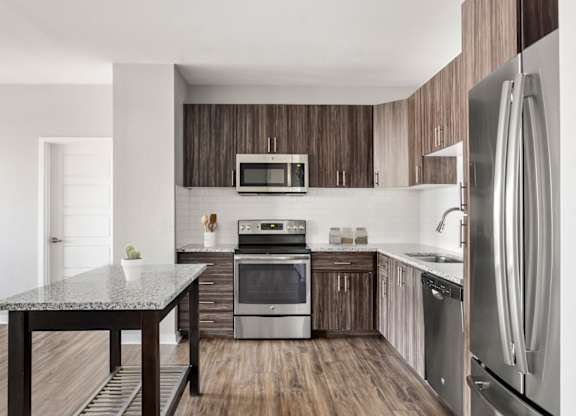 A modern kitchen with a granite table and stainless steel appliances.