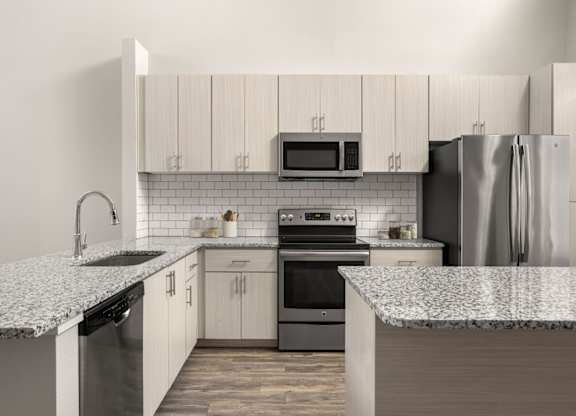 A kitchen with a granite countertop and stainless steel appliances.