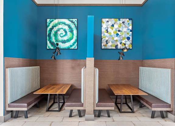 A blue room with two benches and two paintings hanging on the wall.