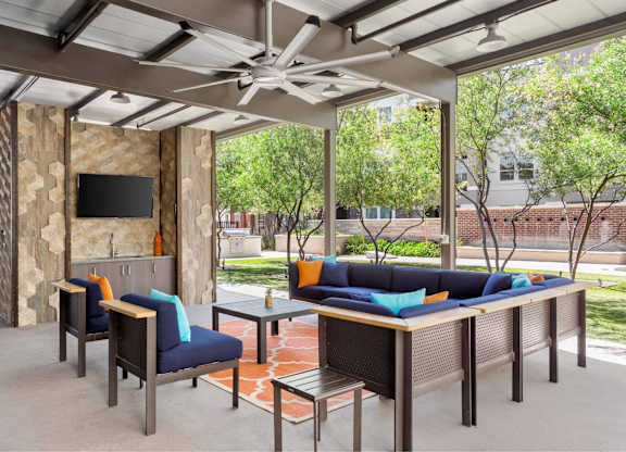 A patio with a couch, chairs, and a television.