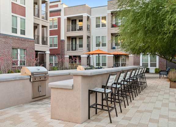 A patio with a bar and chairs is surrounded by apartment buildings.