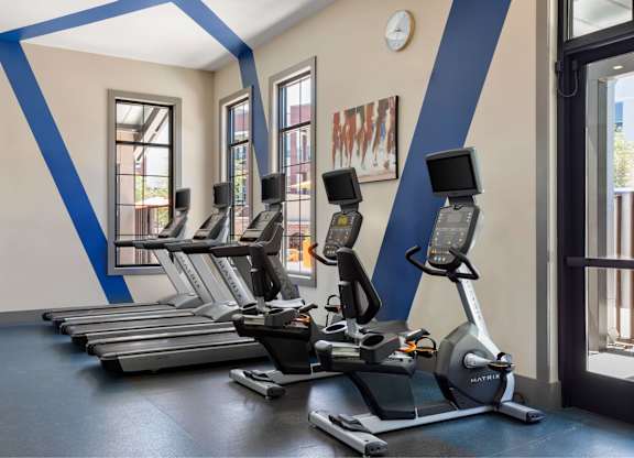 A gym with treadmills and a clock on the wall.