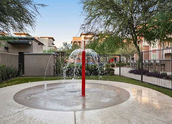 A water fountain in the middle of a paved area.