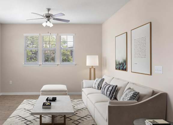 A living room with a couch, a coffee table, and a ceiling fan.