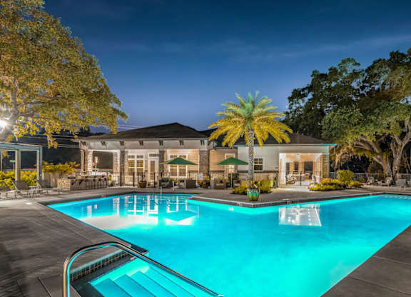 A large swimming pool in front of a building with trees around it.