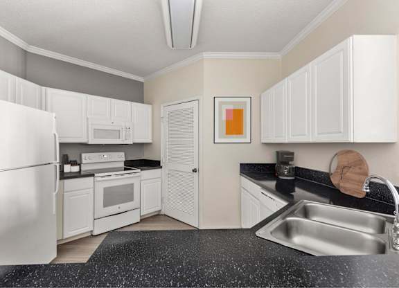A kitchen with white cabinets and a black countertop.