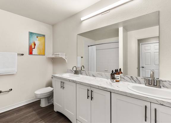 A bathroom with a toilet, sink, and a mirror.