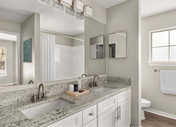 A bathroom with a granite countertop and a large mirror.