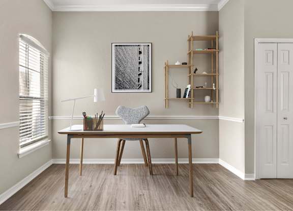 A room with a table, a chair, and a shelf with a picture frame on the wall.