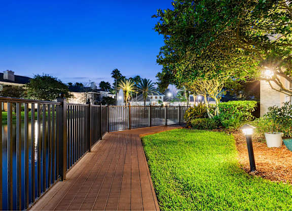 A walkway with lights and a fence next to a body of water.