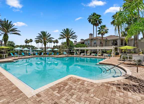 A large swimming pool surrounded by palm trees and lounge chairs.