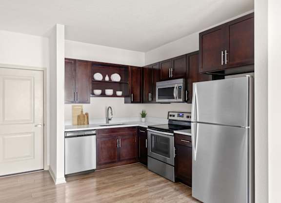 A kitchen with a refrigerator, oven, and sink.