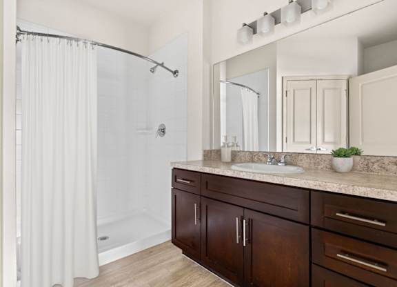 A bathroom with a white shower curtain and a brown vanity.