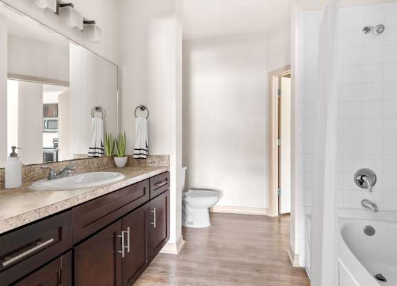 A bathroom with a white tub, sink, and toilet.