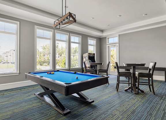 A pool table in a room with a chair and a dining table.