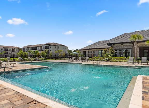 A large swimming pool with a fountain in the middle and chairs around it.