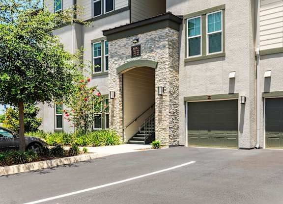 A modern two-story house with a stone archway entrance and two garage doors.