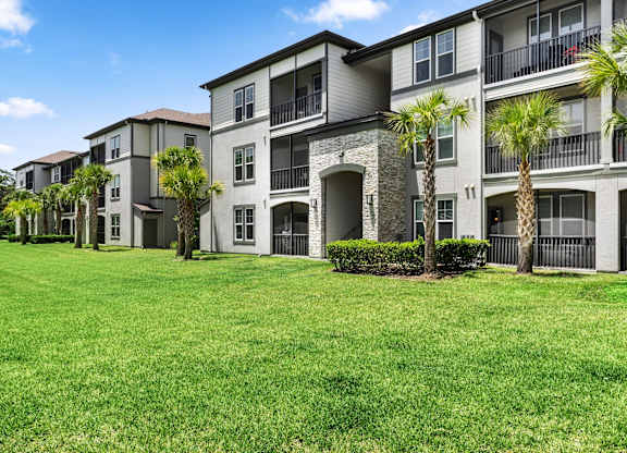 A row of apartment buildings with green lawns in front.