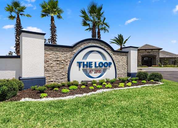 A sign for The Loop at 2700 with a blue sky and palm trees in the background.