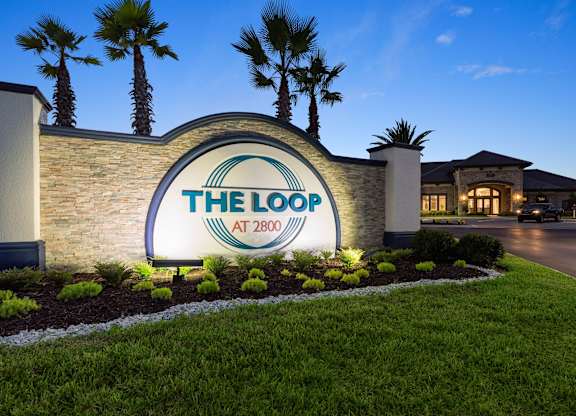 The entrance to The Loop at 2800 with a sign and palm trees.