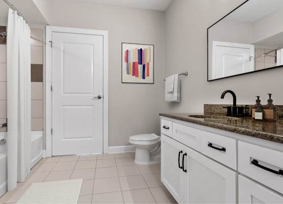 A bathroom with a white door, a toilet, a sink, and a mirror.