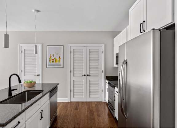 A modern kitchen with a stainless steel refrigerator and wooden floors.