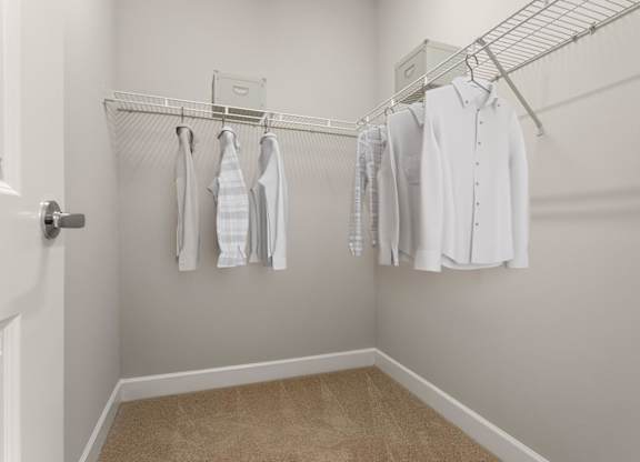 A white closet with clothes hanging on a wire rack.