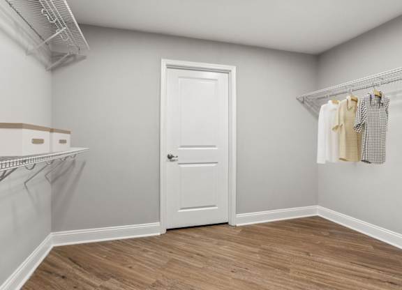 A room with a white door and a wooden floor.
