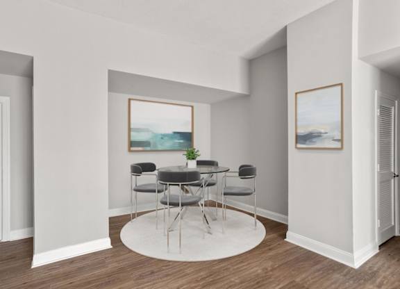 A room with a table and chairs and a painting on the wall.