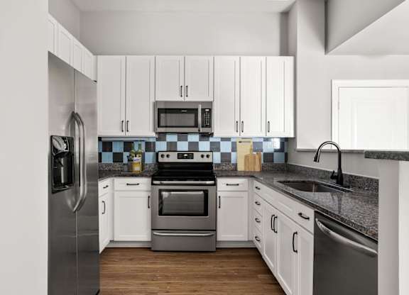 A modern kitchen with white cabinets and stainless steel appliances.