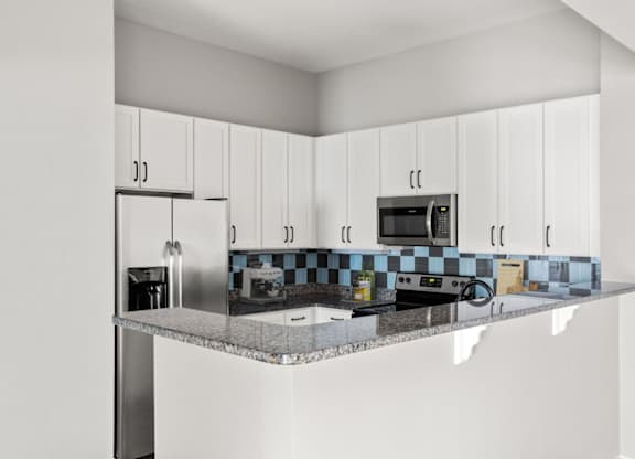 A kitchen with white cabinets and a checkered backsplash.