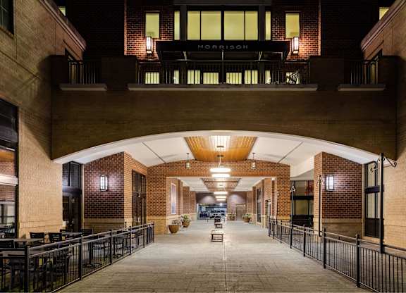 A long hallway with tables and chairs on either side leading to a door at the end.