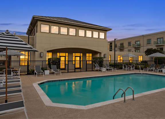 A swimming pool is surrounded by lounge chairs and umbrellas.