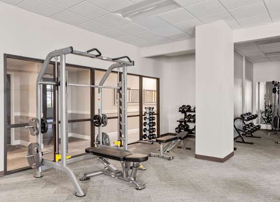 A gym with a variety of equipment including a squat rack, bench, and weights.