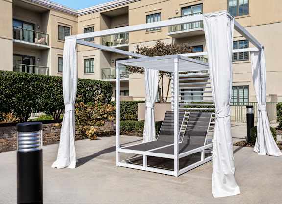 A white canopy structure with draped white fabric is in front of a building.