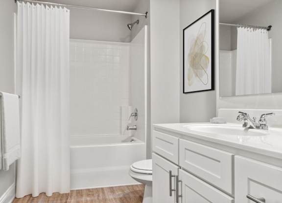 A white bathroom with a toilet, sink, and shower.